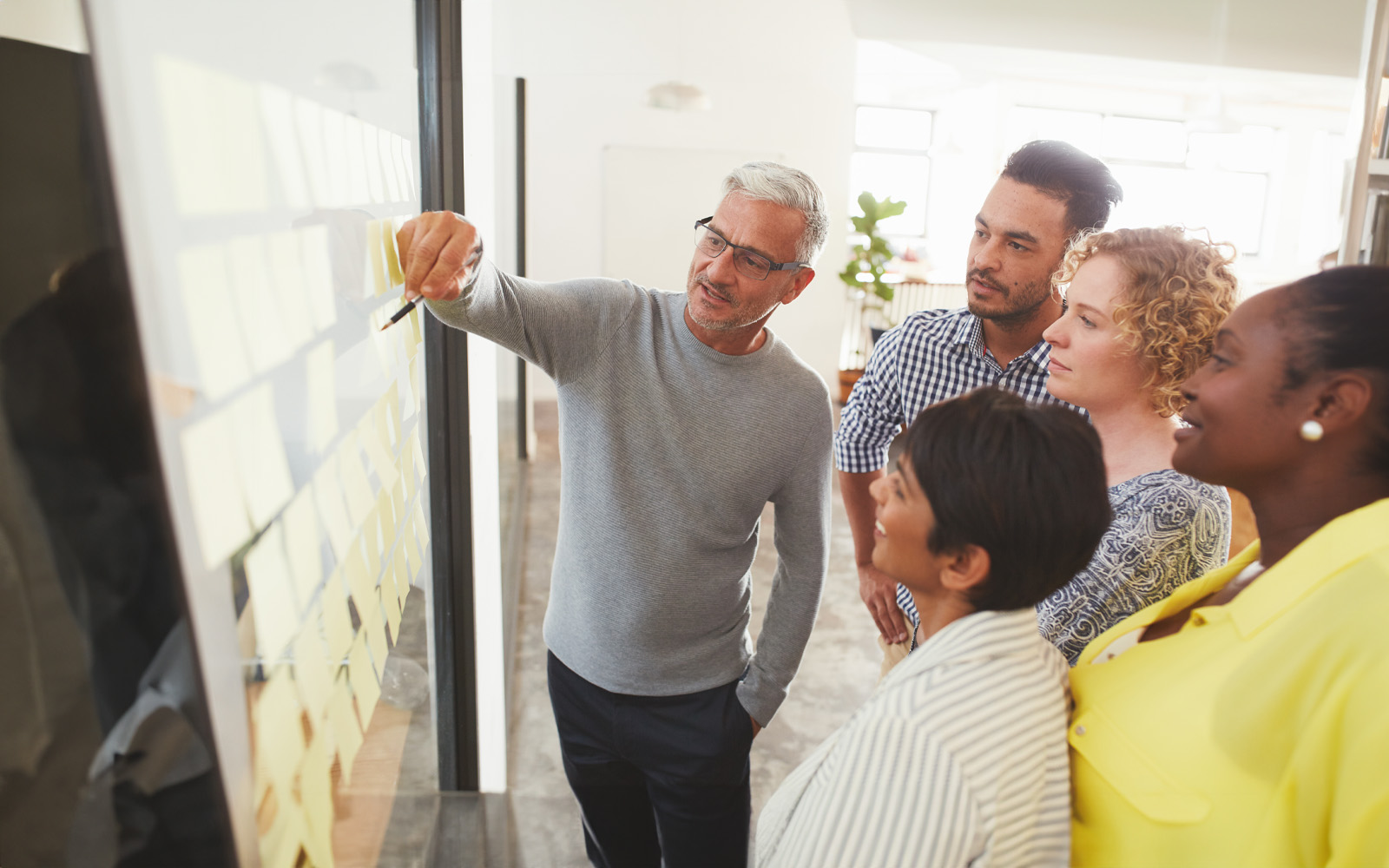 businesspeople-brainstorming-with-adhesive-notes-in-a-meeting-1180532869