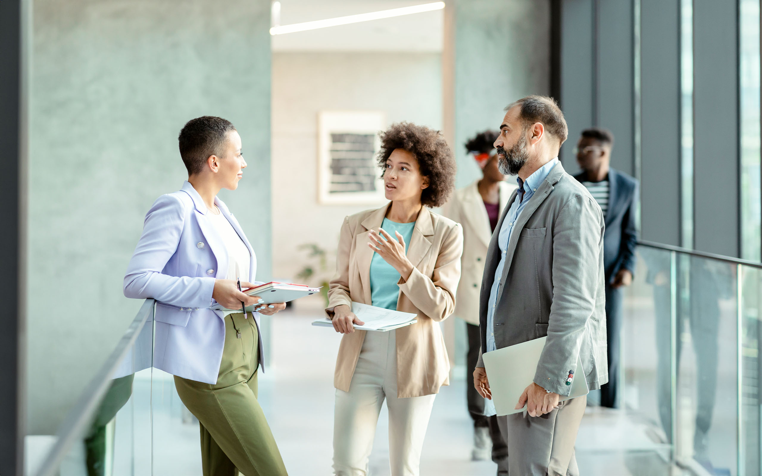 businesspeople-discussing-work-while-standing-together-1322536210