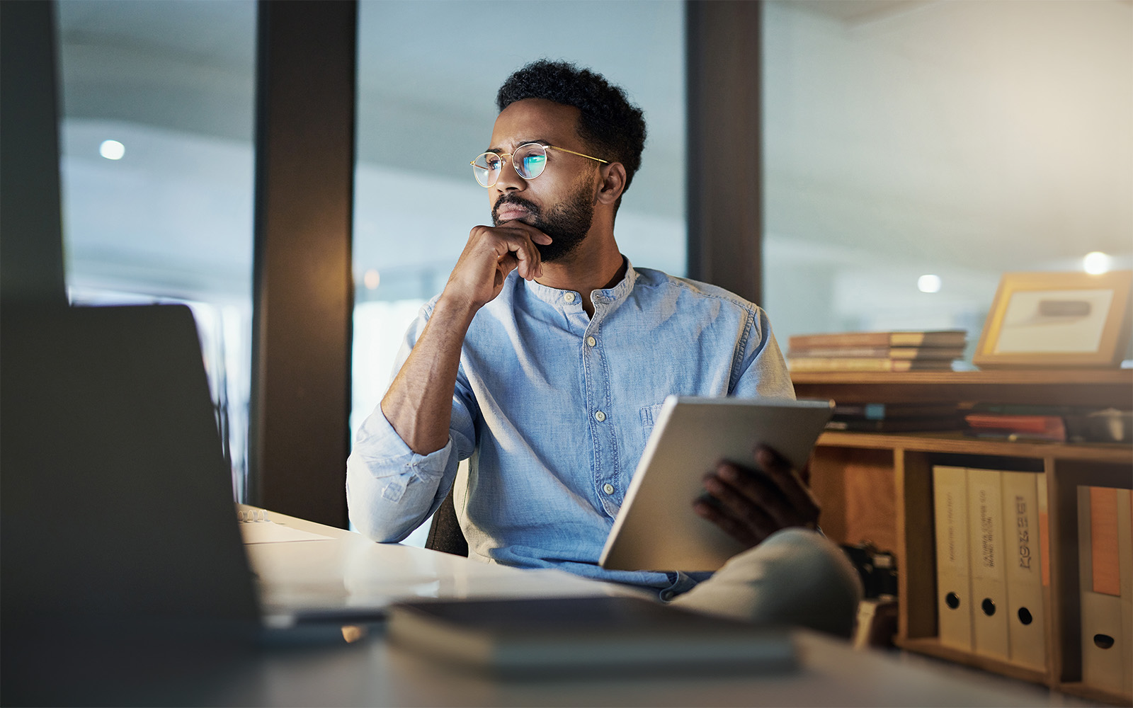 Mann sitzt konzentriert am Laptop und hält Notizen fest.