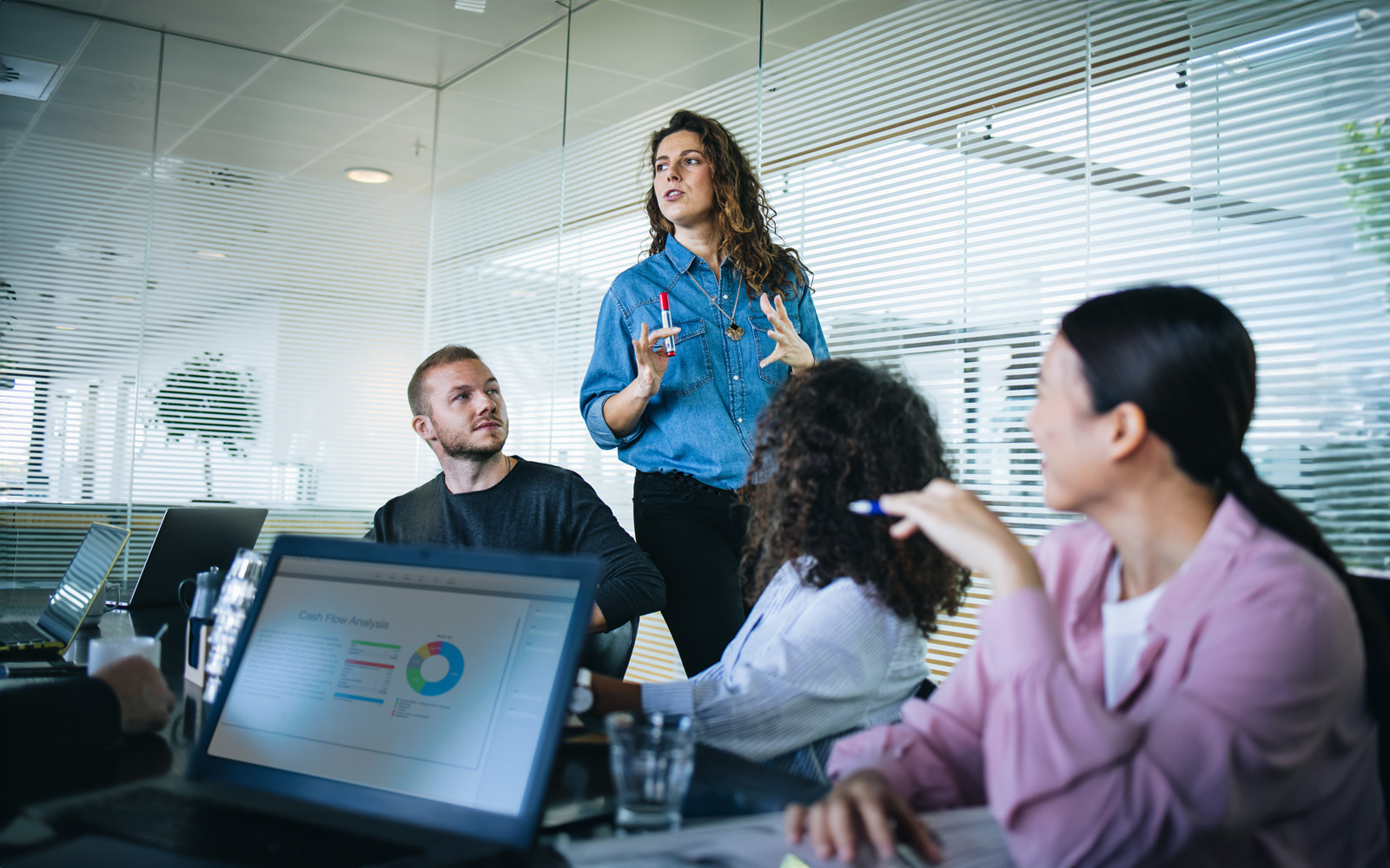 businesswoman-sharing-new-ideas-with-team-in-presentation-1308966425
