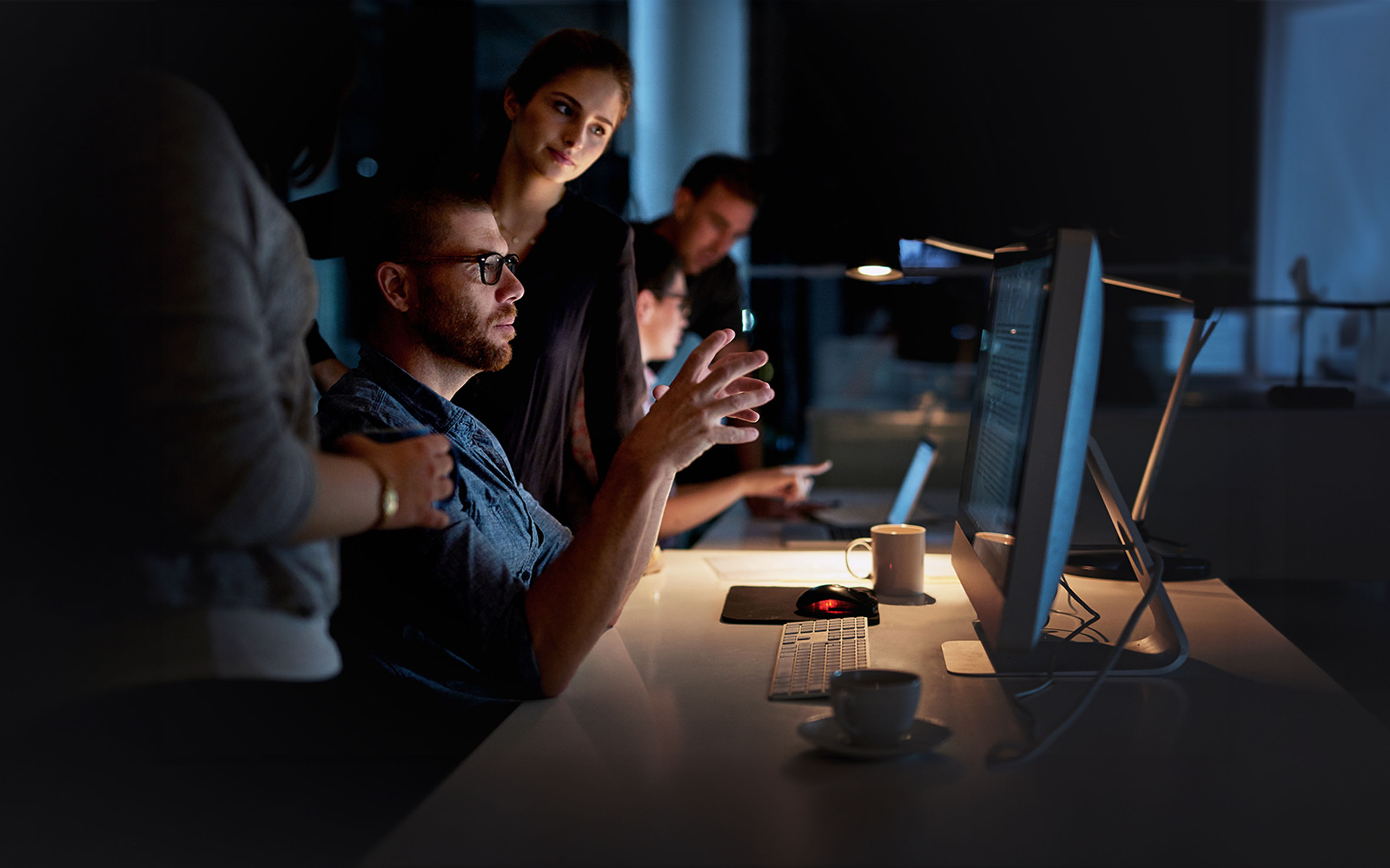 colleagues-using-computer-late-at-work-815671572