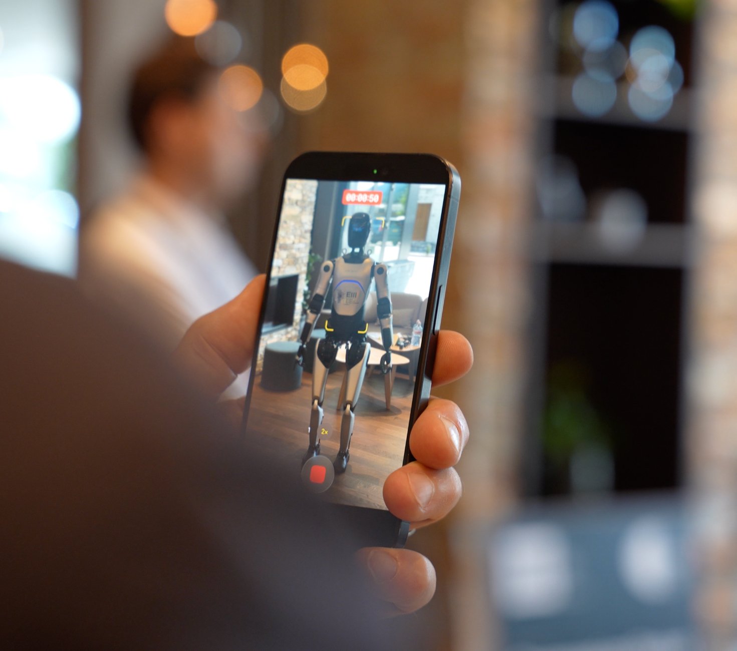 Person holding a phone with an embodied robot on screen.