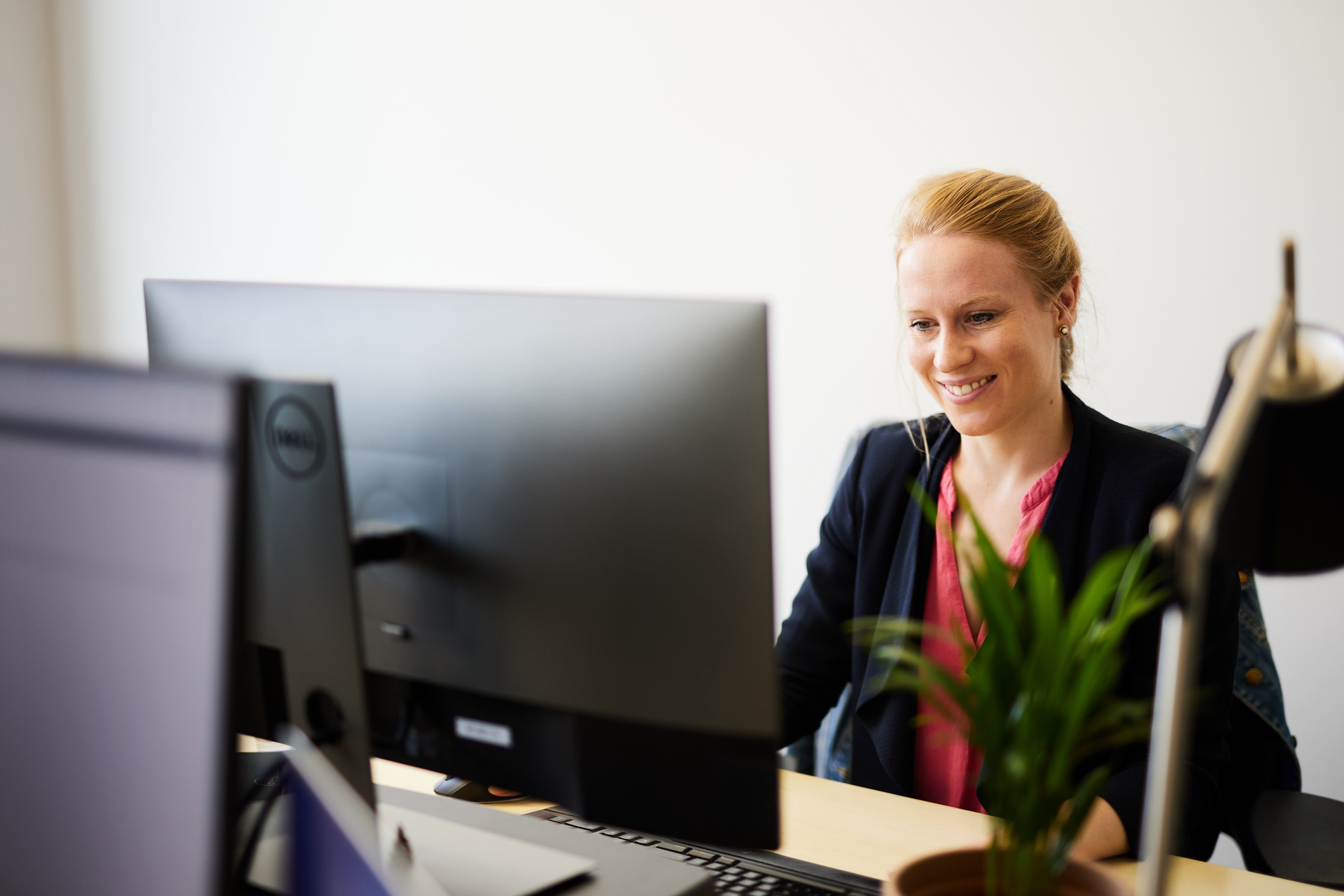 im Dokument ist ein Foto einer lächelnden Frau zu sehen, die vor einem Computer sitzt.