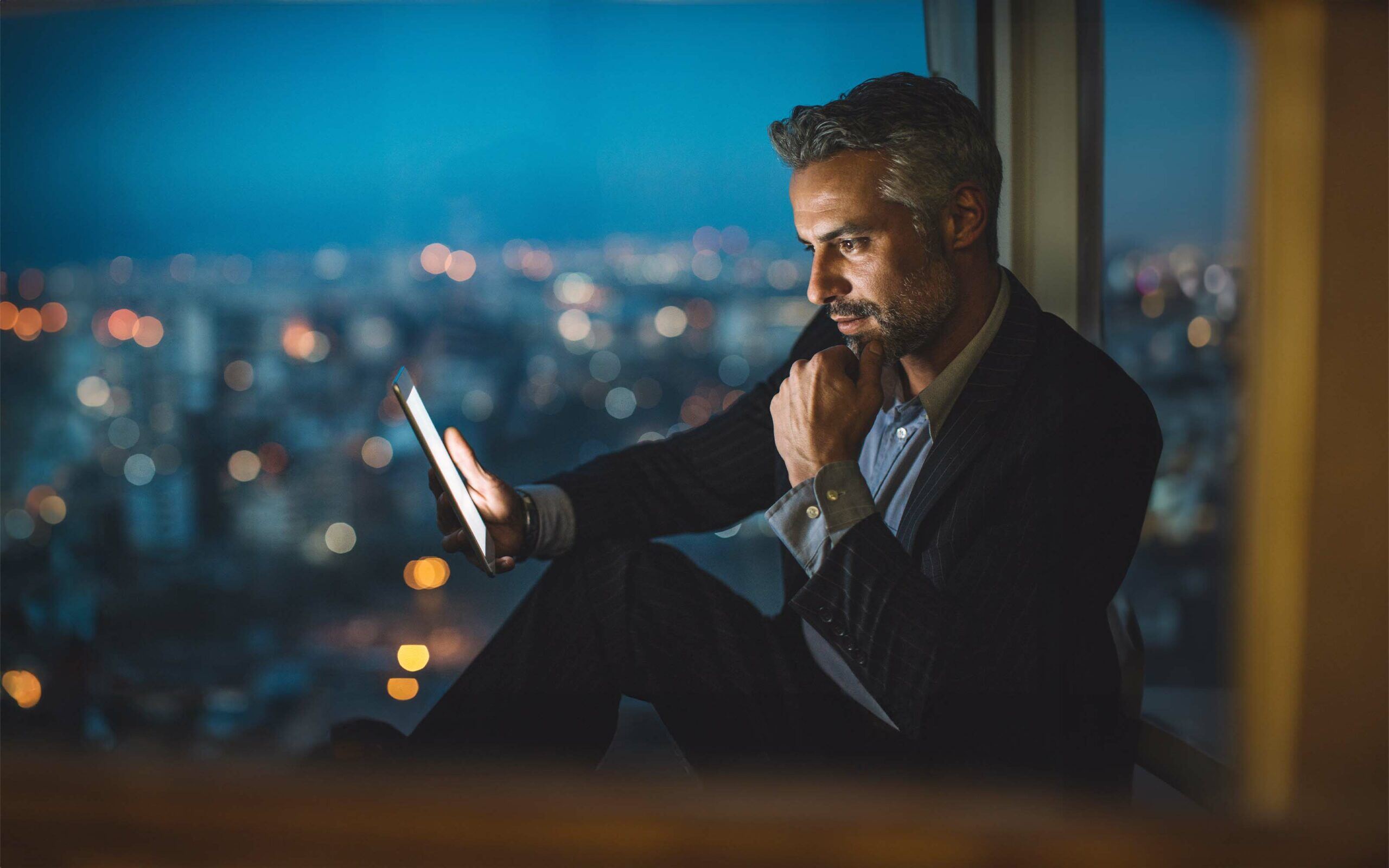 businessman-looking-at-digital-tablet-at-night-624978806-scaled