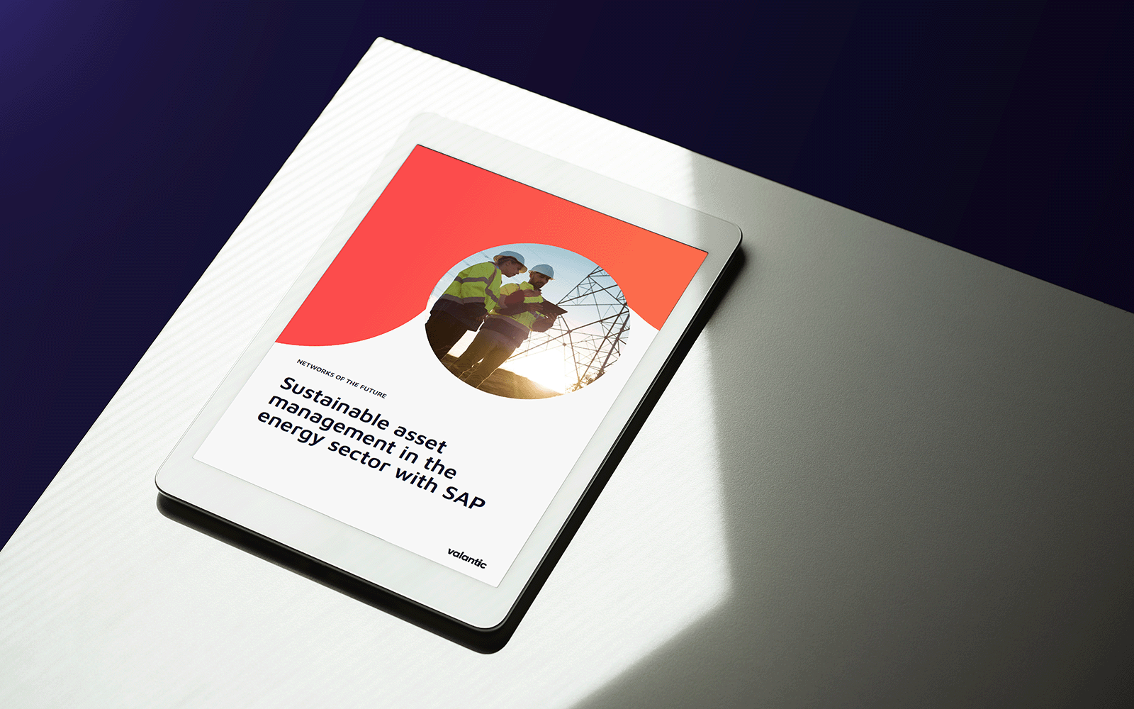 Two people in work clothes, holding an iPad, talk about asset management in the energy sector while the sun sets in the background.